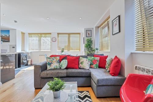a living room with a gray couch with red pillows at Urban Heights By My Getaways in Brighton & Hove