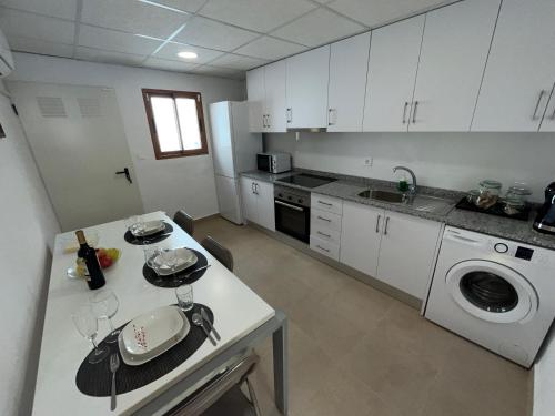 a kitchen with white cabinets and a table with wine glasses at Alojamiento La Cartera I Alto del Garruchal in El Caracolero