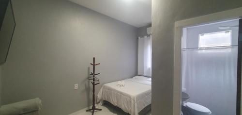 a small white room with a bed and a cross at Hotel Bella Júlia in Joinville