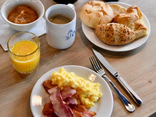 Una mesa con dos platos de huevos, tocino y pan. en ibis Styles Saint Nazaire Centre Gare, en Saint-Nazaire