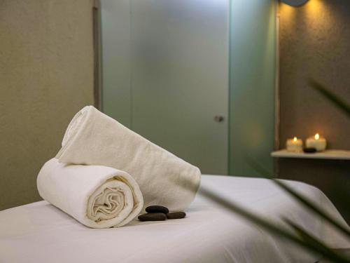 a towel sitting on top of a bed with candles at Mercure Rosario in Rosario