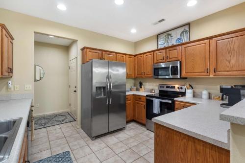 a kitchen with wooden cabinets and a stainless steel refrigerator at Stonebridge Hideaway - For 6 in Branson West