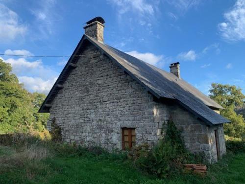 a small stone house with a roof on a field at La maison des Florentins La Monédière in Chaumeil
