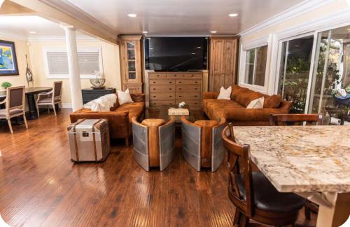 a living room with leather furniture and a flat screen tv at Sac Camp Delta Garden Retreat in Sacramento