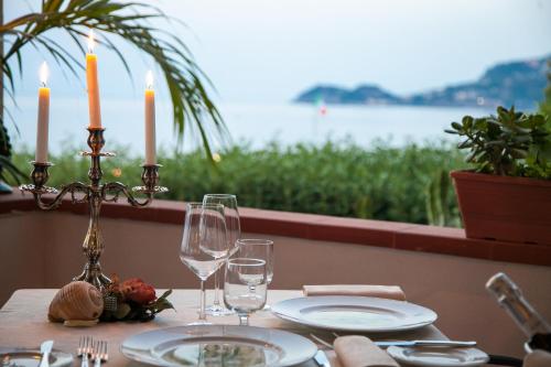 a table with two candles and plates and wine glasses at Park Hotel Silemi in Letojanni