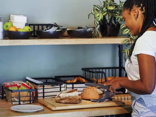 a woman cutting a loaf of bread with a knife at Hotel Valkenburg by Mercure - Next to Shimano Experience Center in Valkenburg