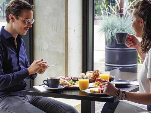 a man and woman sitting at a table eating food at Hotel Valkenburg by Mercure - Next to Shimano Experience Center in Valkenburg