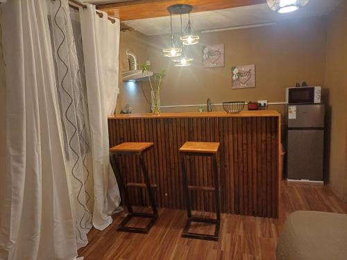 a kitchen with a bar with two stools and a refrigerator at Trich Studio in La Gaulette