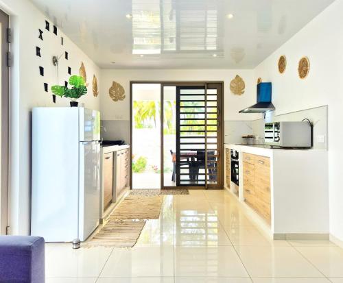 a kitchen with white appliances and a refrigerator at Un écrin de paix au soleil et proche de la mer in Moorea