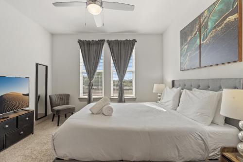 a white bedroom with a bed and a tv at Luxury Apartments Near Airport in Austin