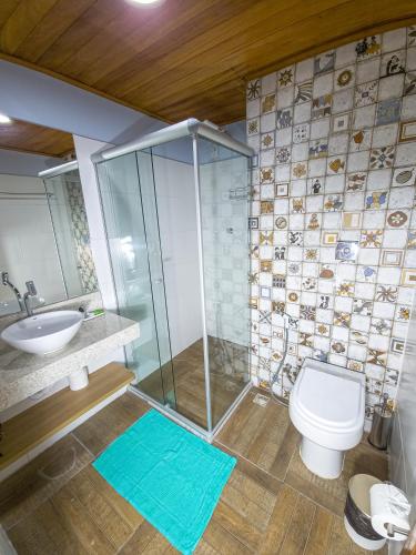 a bathroom with a shower and a toilet and a sink at Pousada Céu da Chapadha in Mucugê