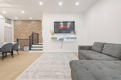 a living room with a couch and a tv on a wall at Top Rated Vacation House Montreal Private Parking in Laval