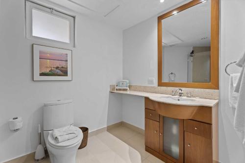 a bathroom with a toilet and a sink and a mirror at Beachfront - Best Beach View Studio - E422-1 in Palm-Eagle Beach