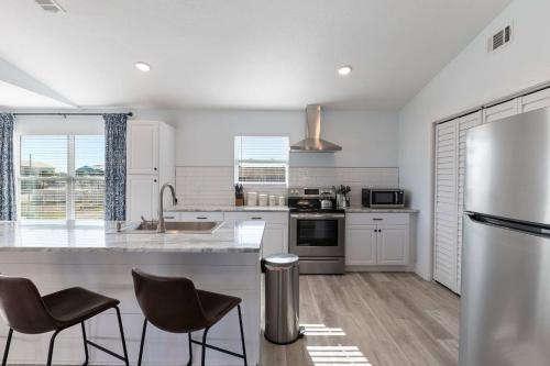 a kitchen with a refrigerator and two bar stools at Blue Beak Bungalow in Pensacola