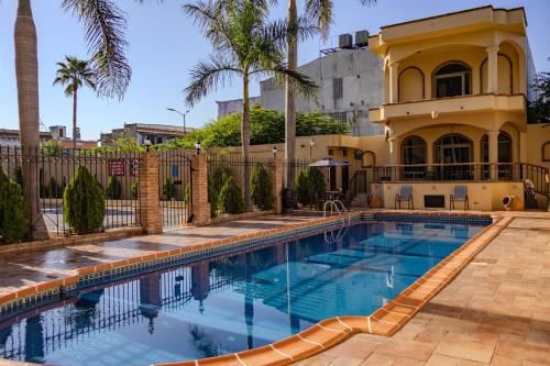 a swimming pool in front of a house with palm trees at Best Western Hotel Plaza Matamoros in Matamoros