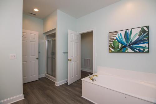 Un baño con paredes blancas y un cuadro en la pared. en Suite Caroline, en Edisto