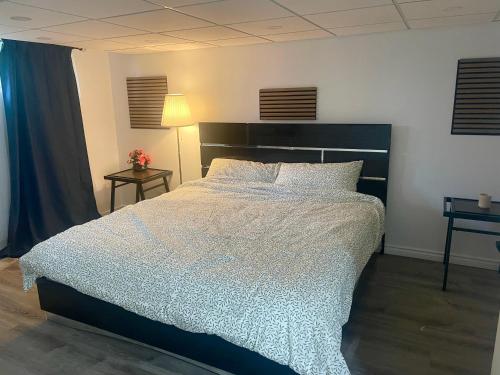 a bedroom with a large bed with a white comforter at Modern & Cozy Basement Suite Lower Unit - 3 rooms -1 King bed - 2 Car Parking in Pickering