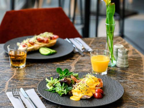 Una mesa con dos platos de comida y una porción de pizza. en Mercure Tokaj Center, en Tokaj