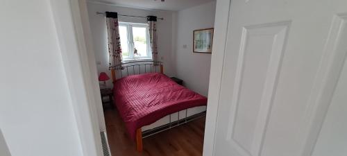 une petite chambre avec un lit avec une couverture rouge dans l'établissement Wren Cottage, à Hindhead
