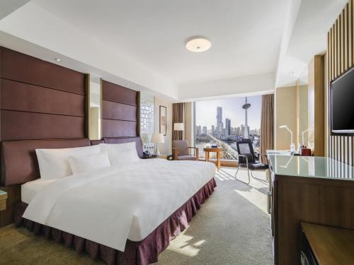 a hotel room with a large bed and a television at Swissôtel Shenyang in Shenyang