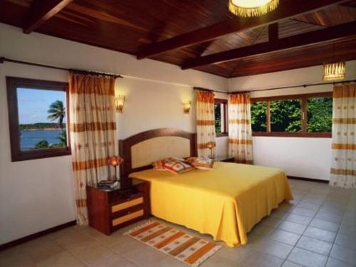 ein Schlafzimmer mit einem gelben Bett in einem Zimmer mit Fenstern in der Unterkunft Lagoa Eco Village in Pipa
