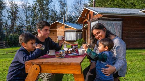 una familia sentada en una mesa comiendo en una mesa de picnic en Turismo Jaos Cabañas Tinas y Quincho, en Futrono