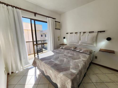 a bedroom with a bed and a large window at Sobrado 30 m praia, quartos climatizados, 1 vaga, até 6 pessoas in Bombinhas