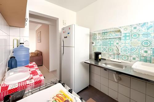a kitchen with a refrigerator and a sink at Apto com AR, 3/4 em condomínio com piscina e lazer in Aracaju