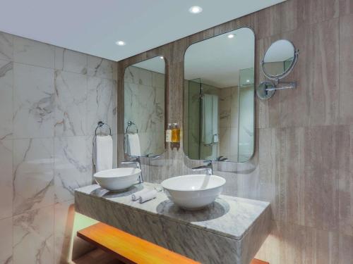 une salle de bain avec deux lavabos et un grand miroir dans l'établissement Queen Elizabeth 2 Hotel, à Dubaï
