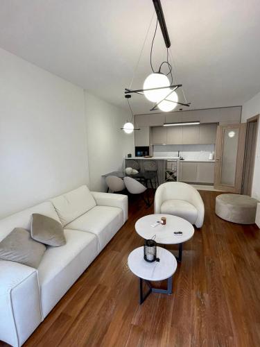 a living room with a white couch and two tables at StayPoint Apartment in Podgorica