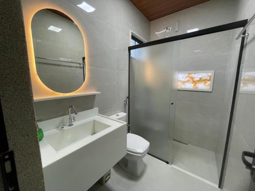 a bathroom with a sink and a toilet and a mirror at Belíssimo Estudio Stella Maris in Andradina