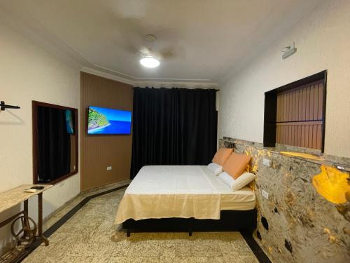 a bedroom with a bed and a tv on the wall at Belíssimo Estudio Stella Maris in Andradina