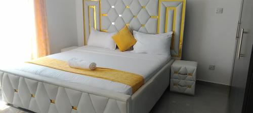Un dormitorio con una gran cama blanca con almohadas amarillas. en AQUA GARDENS SEAVIEW LUXURIOUS HOMESTAY NYALI Msa, en Mombasa