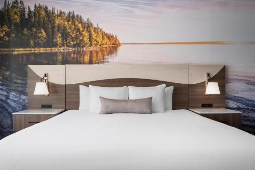 a bedroom with a large white bed and a lake at Best Western Premier Bridgewood Hotel Resort in Neenah