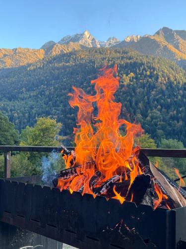 a fire is burning in a grill with mountains in the background at Mtis Racha in Oni