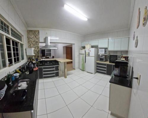 a large kitchen with white tile floors and white appliances at Casa da Rosa in Goiânia