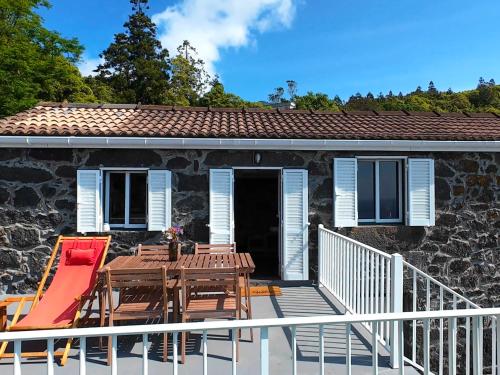 a deck with a table and chairs on a house at Casa das Duas Ribeiras in Lajes do Pico