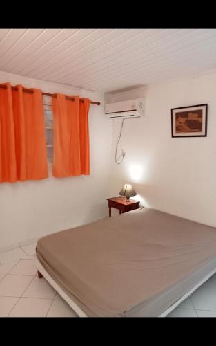 a bedroom with a bed and a window and a lamp at Les jardins de VALENTIN in Le Gosier