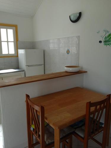 a kitchen with a wooden table and two chairs at Les jardins de VALENTIN in Le Gosier