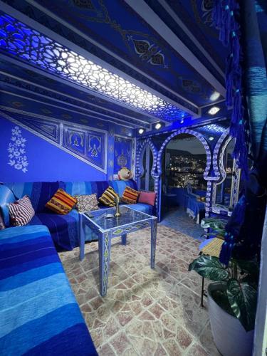 ein blaues Zimmer mit einem Tisch und einem Sofa in der Unterkunft DAR AMRANi in Chefchaouen