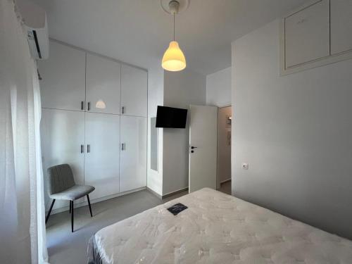 Un dormitorio blanco con una cama y una silla. en Loutraki's Seaside Serenity, 2 BDRM apartment, en Loutraki