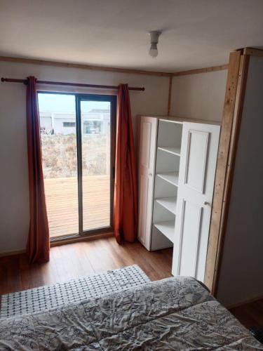 ein Schlafzimmer mit einem Bett und einer Glasschiebetür in der Unterkunft Cabaña en Playa Totoralillo in Totoralillo