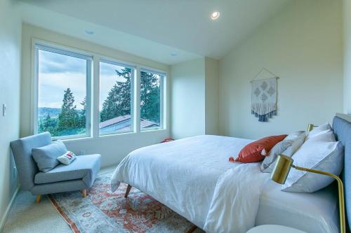 a bedroom with a bed and a chair and windows at 3 min to UO with amazing views! Central to all! in Eugene