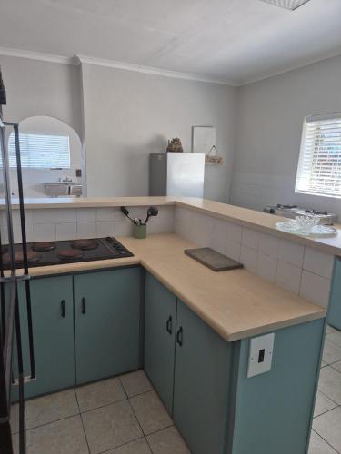 a kitchen with blue cabinets and a counter top at Magna Apartment in Jeffreys Bay