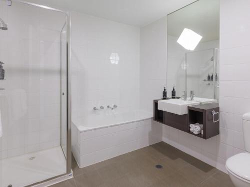 une salle de bain blanche avec une baignoire et un lavabo dans l'établissement Mantra Melbourne Melton, à Melton