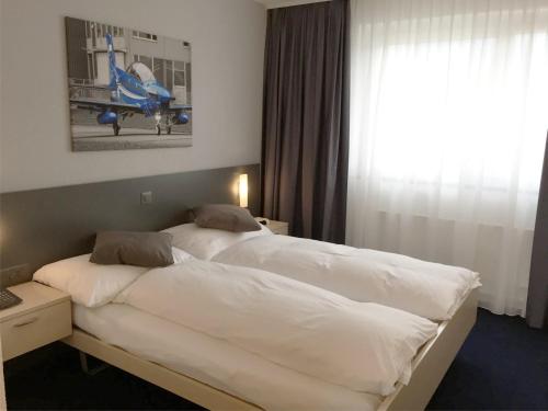 a hotel room with two beds and a window at Airporthotel Grenchen in Grenchen