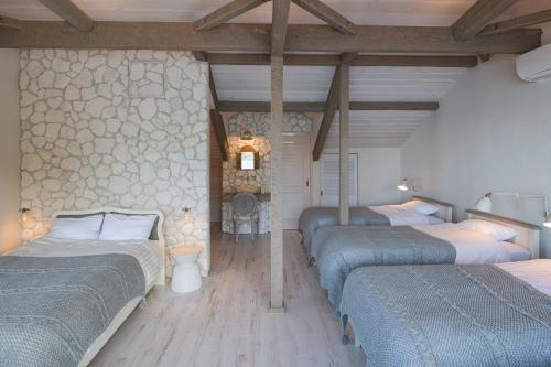 3 Betten in einem Zimmer mit einer Steinmauer in der Unterkunft COVE KAWANA - Vacation STAY 69198v in Kawana