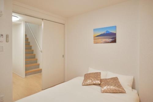 a white bedroom with a bed and a staircase at J-ARC Akebonobashi - Vacation STAY 17362 in Tokyo