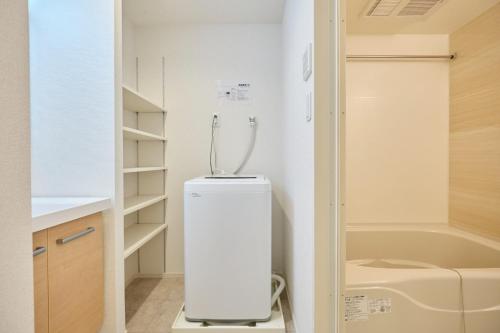 a small white refrigerator in a bathroom next to a bath tub at J-ARC Akebonobashi - Vacation STAY 17362 in Tokyo