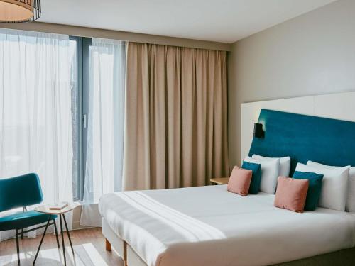 a hotel room with a large bed and a blue headboard at Aparthotel Adagio Glasgow Central in Glasgow